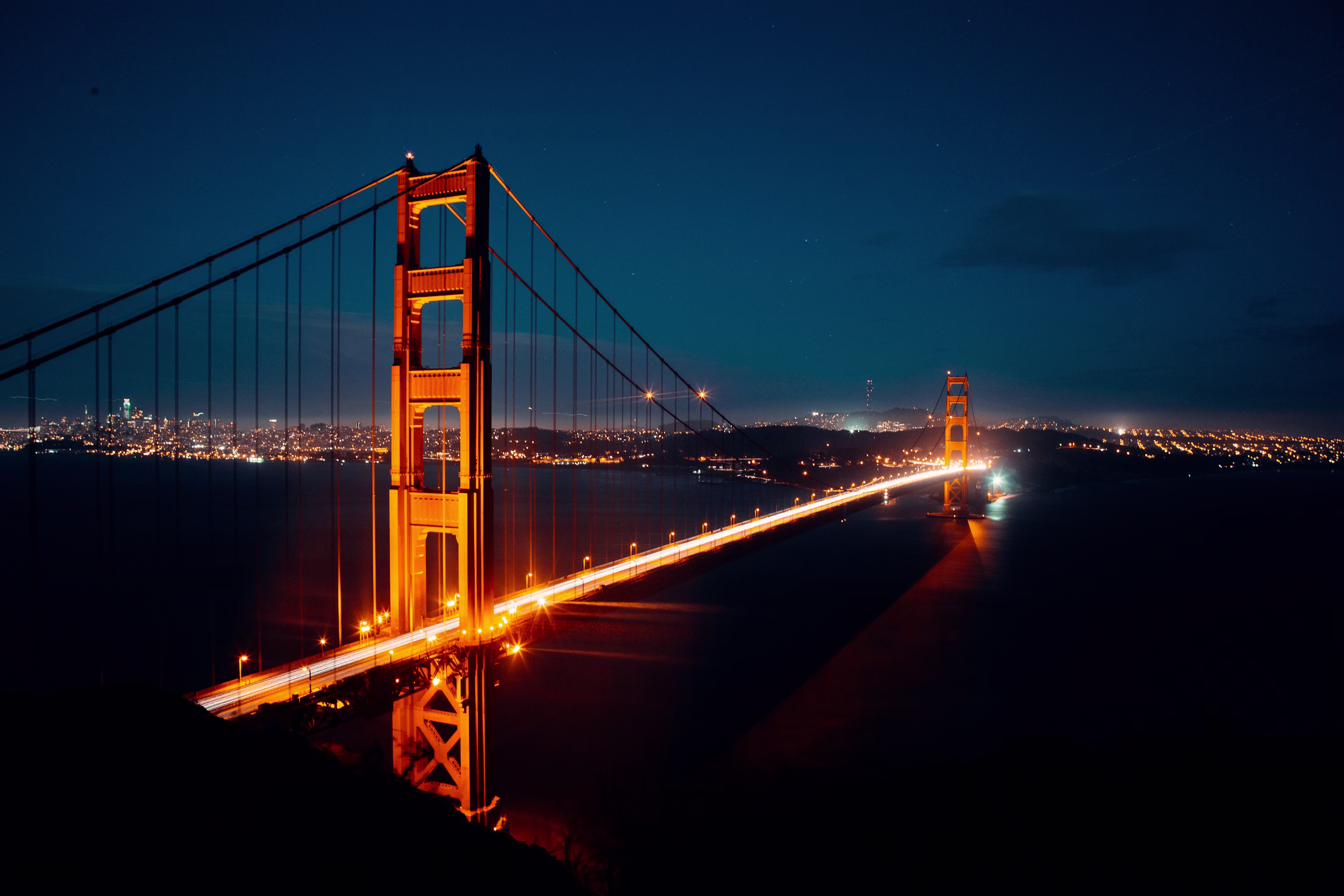 The Golden Gate Bridge at night with the San Francisco skyline behind